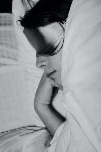 how to sleep better at night - woman sleeping with silk face mask in black and white